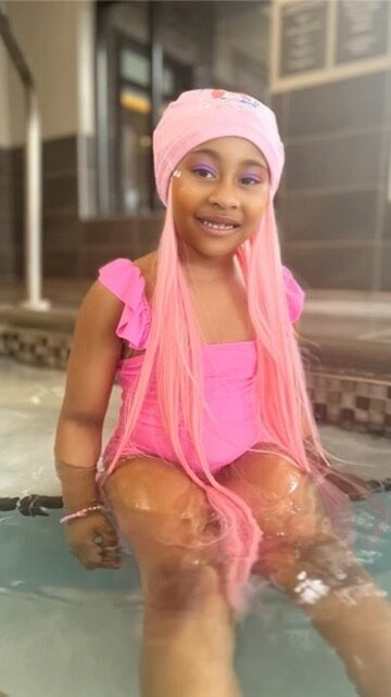 Black girl in SwimHair cap sitting at the pool — hair totally dry